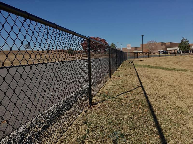 Black chain link fence installed along paved walkway at commercial property in Chicagoland