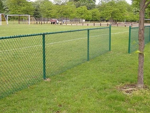 Green vinyl-coated chain link fence surrounding sports field in Chicagoland area