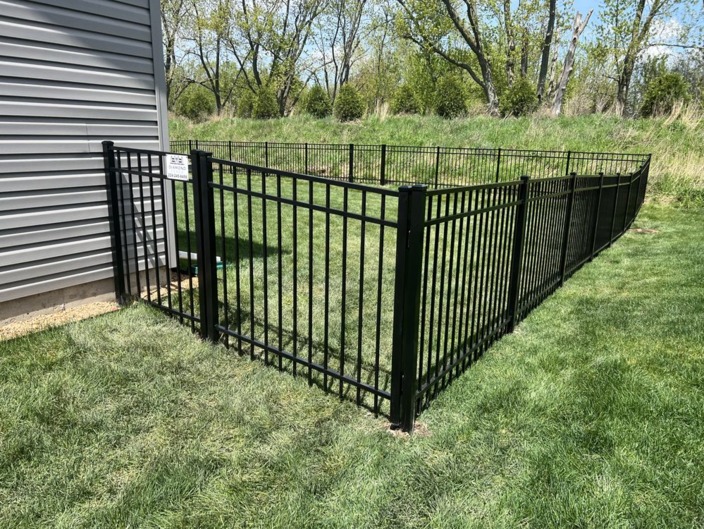 Newly installed black aluminum safety fence enclosing above-ground pool area on lush green lawn — includes gate access, clean lines, and durable powder-coated finish; perfect for family homes needing code-compliant protection
