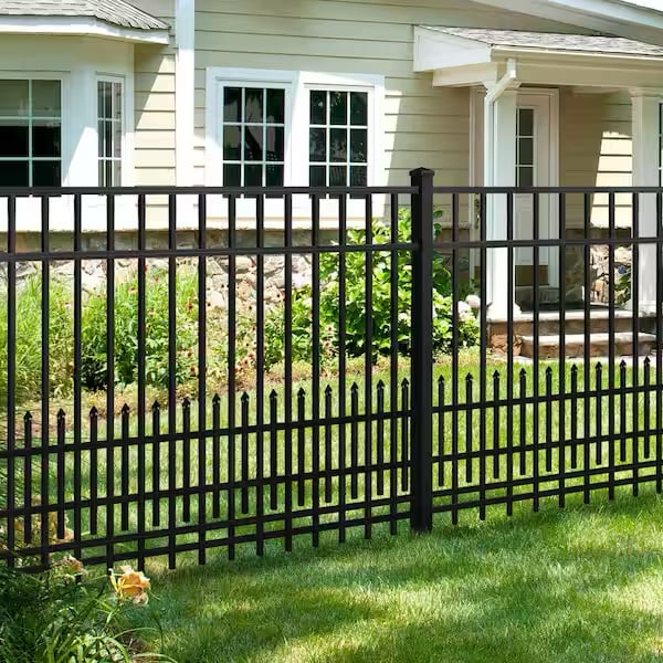 Black aluminum picket fence with spear-shaped tops installed in front of beige house with stone foundation